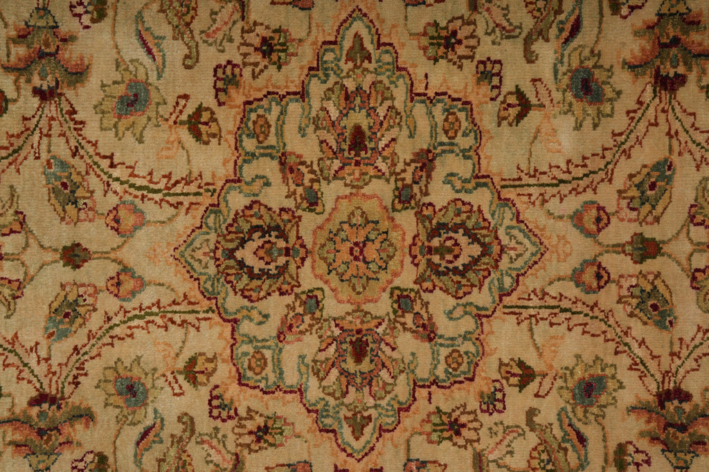 A close-up of a traditional patterned rug with a central medallion and floral motifs in beige, brown, muted green, and dusty blue.