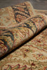 Load image into Gallery viewer, A close-up of a rolled section of a traditional patterned area rug, showing its detailed woven design in beige, green, red, and brown tones over a dark wood floor.