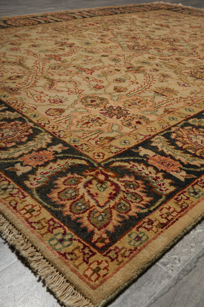 A traditional oriental-style area rug with a beige base and ornate floral motifs in red, green, and dark blue, shown laid out on a gray tiled floor.