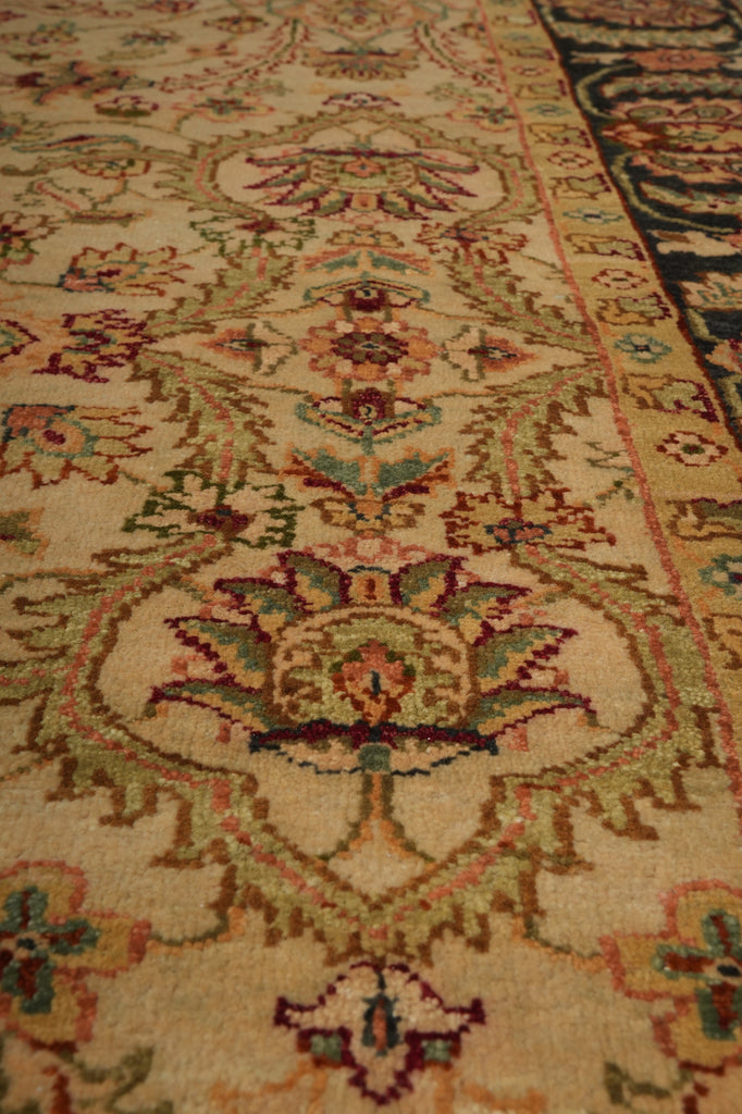A close-up view of an ornate traditional area rug with a beige background and intricate floral motifs in muted green, terracotta, and dark blue.