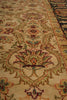 Load image into Gallery viewer, A close-up view of an ornate traditional area rug with a beige background and intricate floral motifs in muted green, terracotta, and dark blue.