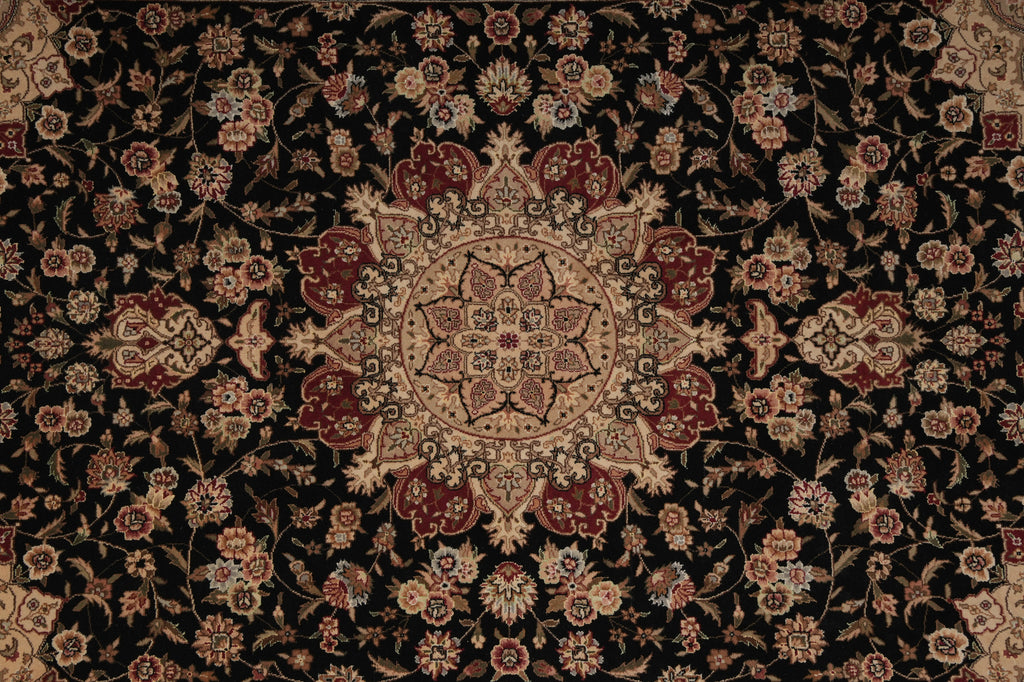 A traditional oriental rug with an intricate floral pattern on a black background, featuring a central medallion and surrounding floral motifs in beige, rust red, and muted blue.