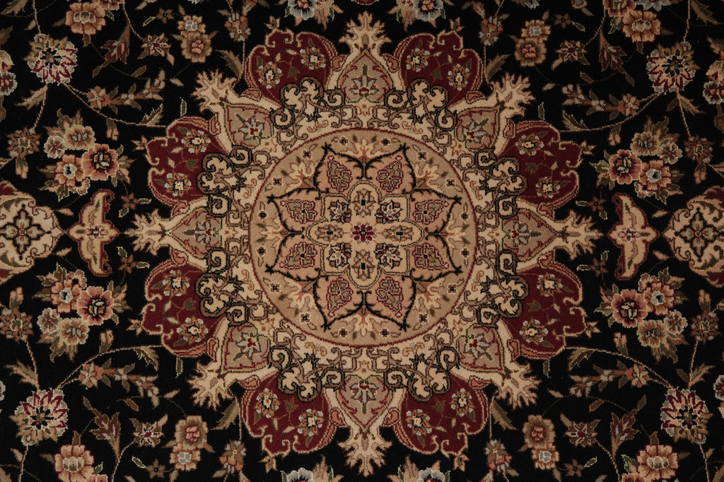 A close-up of an ornate traditional rug featuring a central medallion and floral motifs in deep burgundy, beige, and black.
