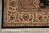 Load image into Gallery viewer, Close-up of an ornate patterned area rug corner showing cream, beige, black, and muted red floral motifs with a fringed edge on a gray floor.