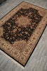 Load image into Gallery viewer, A rectangular traditional area rug with an intricate floral pattern, featuring a black center field, beige and brown borders, and cream fringe, shown laid out on a gray wood-look floor.