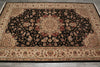 Load image into Gallery viewer, A traditional oriental area rug with an intricate floral pattern, featuring a large black central field, beige borders, and red and gold accents, laid out on a gray tiled floor.