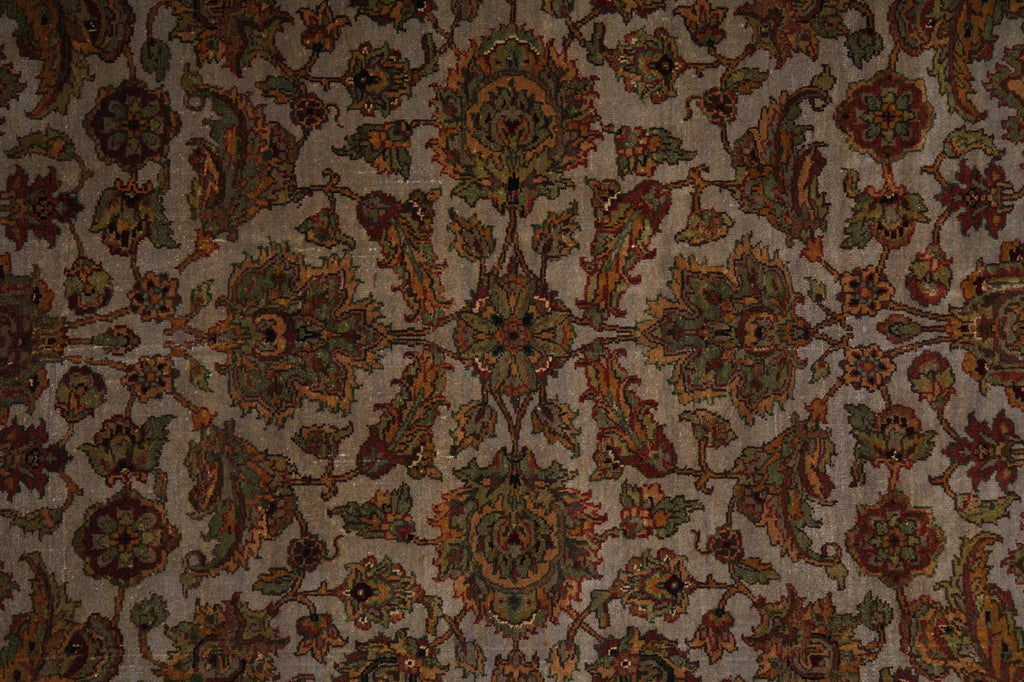 An ornate traditional patterned rug with a central medallion and surrounding floral motifs in muted earthy tones of brown, olive green, rust orange, and beige.