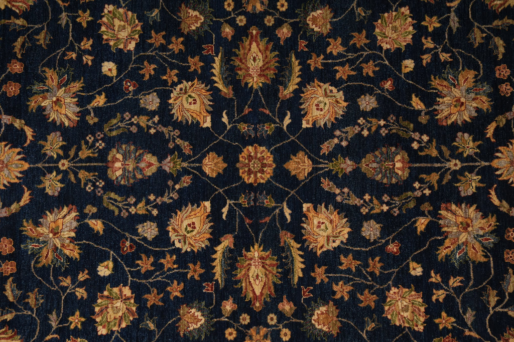A close-up of an ornate floral patterned fabric or rug with a dark navy blue background and intricate gold, beige, and rust-colored botanical motifs.