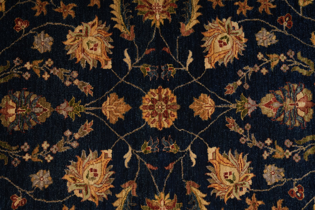 A close-up of a dark navy blue patterned rug with an ornate floral design in beige, rust, and muted green.