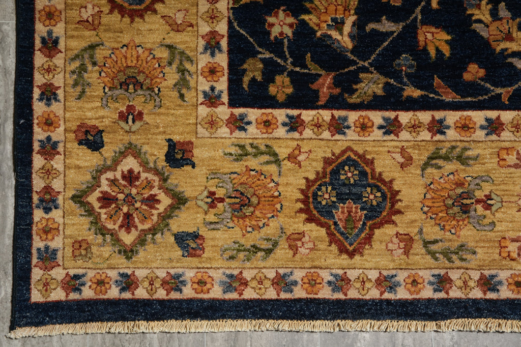 Close-up of a traditional patterned rug corner showing a beige field with floral motifs, a dark navy border, and multicolored medallions and vine details.