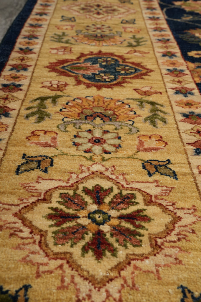 A close-up view of a traditional patterned area rug with a warm beige base, featuring large central medallions and floral motifs in red, blue, green, and orange.