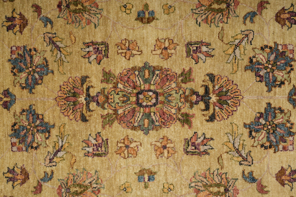 A close-up of a traditional patterned rug with a warm beige background and ornate floral motifs in muted blue, pink, green, and orange.