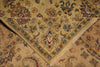 Load image into Gallery viewer, A close-up of an ornate area rug with a warm beige and tan base, featuring intricate floral motifs in muted red, blue, green, and brown, with a fringed triangular border.
