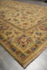 Load image into Gallery viewer, A traditional oriental area rug with a warm mustard yellow base and an intricate floral and medallion pattern in muted red, blue, green, and brown, shown laid out on a gray concrete floor.