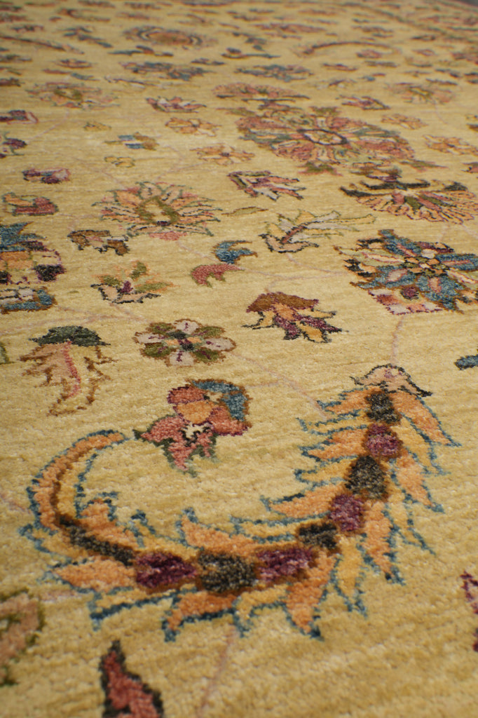 A close-up view of a traditional patterned rug with a warm beige background and multicolored floral and ornamental motifs in muted pink, blue, green, and brown tones.