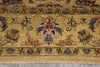Load image into Gallery viewer, A close-up of a traditional patterned rug with a warm mustard yellow base, featuring floral motifs and a central medallion in muted blue, green, and terracotta tones, finished with a fringed edge.