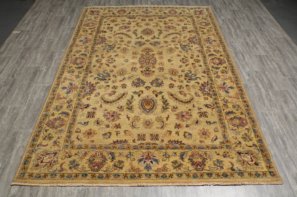 A rectangular vintage-style area rug with an intricate floral and medallion pattern in beige, brown, and muted blue, laid out on a gray wood-look floor.