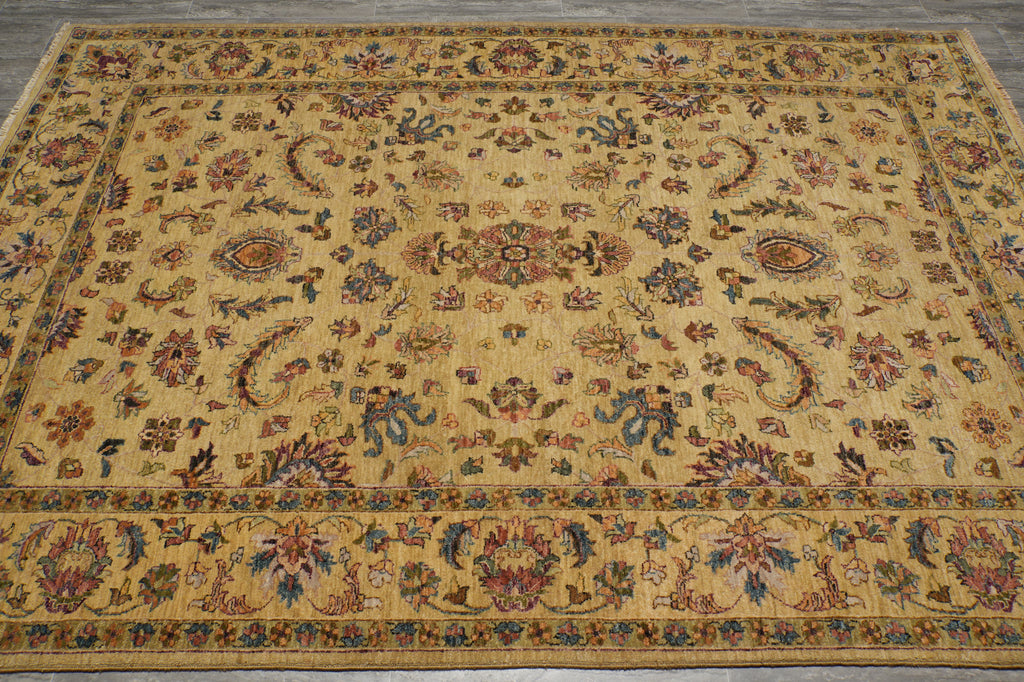 A rectangular vintage-style area rug with an intricate floral and paisley pattern on a warm beige background, featuring blue, red, and green accents.