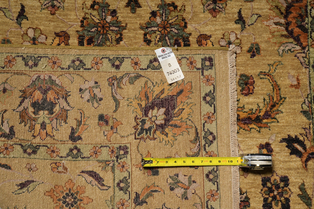 A close-up of a patterned area rug with a beige base and multicolor floral motifs, shown with a measuring tape and a white size tag on a matching rug surface.