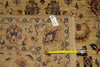 Load image into Gallery viewer, A close-up of a patterned area rug with a beige base and multicolor floral motifs, shown with a measuring tape and a white size tag on a matching rug surface.