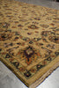 Load image into Gallery viewer, A close-up of a traditional area rug with a warm beige and mustard yellow base, featuring an intricate floral pattern in brown, orange, and green, with a fringed edge on a gray tiled floor.