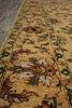 Load image into Gallery viewer, A close-up view of a traditional patterned area rug with a warm mustard yellow base, featuring floral motifs in brown, green, beige, and muted orange, bordered by ornate patterns.
