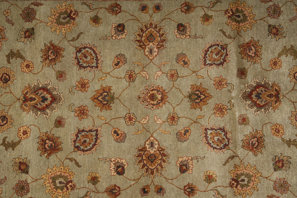 A close-up of an ornate floral patterned fabric or rug in muted earthy tones, featuring a beige-gray base with brown, rust, and olive floral motifs.