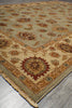 Load image into Gallery viewer, A traditional oriental-style area rug with a beige and olive green base, featuring intricate floral motifs and a detailed border, laid out on a gray tiled floor.