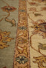 Load image into Gallery viewer, Close-up of an ornate area rug showing a central floral border in beige and gold tones, flanked by a muted sage green section on the left and a cream section on the right.