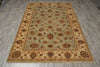 Load image into Gallery viewer, A rectangular area rug with an ornate floral and medallion pattern, laid out on a gray wood-look floor. The rug features a sage green center field, a beige inner border, and a darker brown outer border.