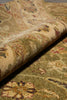Load image into Gallery viewer, A close-up of a rolled area rug showing its detailed vintage-style floral pattern in muted beige, olive green, and rust red tones.