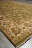 Load image into Gallery viewer, A close-up view of a traditional patterned area rug with a beige and olive green base, featuring floral motifs and fringed edges, laid out on a gray tiled floor.
