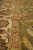 Load image into Gallery viewer, Close-up of a traditional patterned area rug with a cream field, a central floral border in muted red and gold, and an olive green section with botanical motifs.