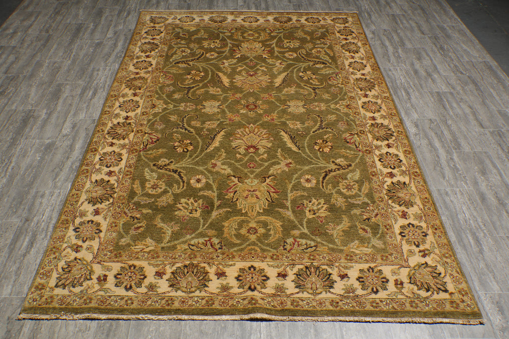 An oriental-style area rug with an intricate floral and vine pattern, shown laid out on a gray wood-look floor. The rug features a dominant olive green center field, a beige border, and accents of brown, gold, and muted red in the detailed motifs.