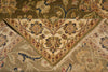 Load image into Gallery viewer, A close-up of an ornate traditional patterned rug or textile shown folded, revealing a cream central field with floral motifs and a border in olive, tan, blue, and rust tones.
