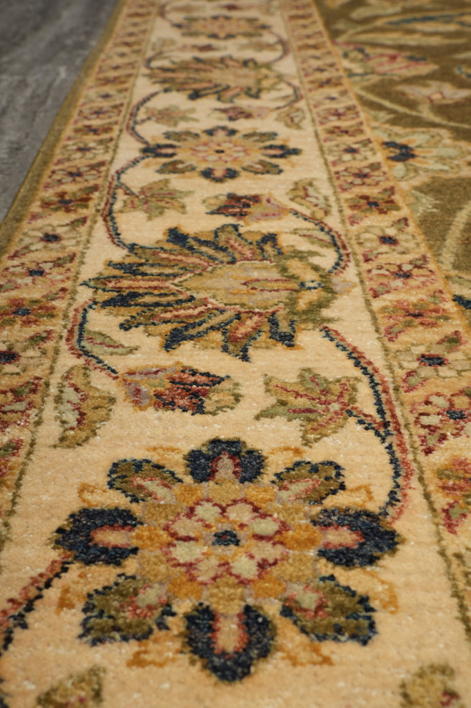 A close-up view of a traditional patterned area rug with a cream base and floral motifs in muted blue, green, and gold tones.
