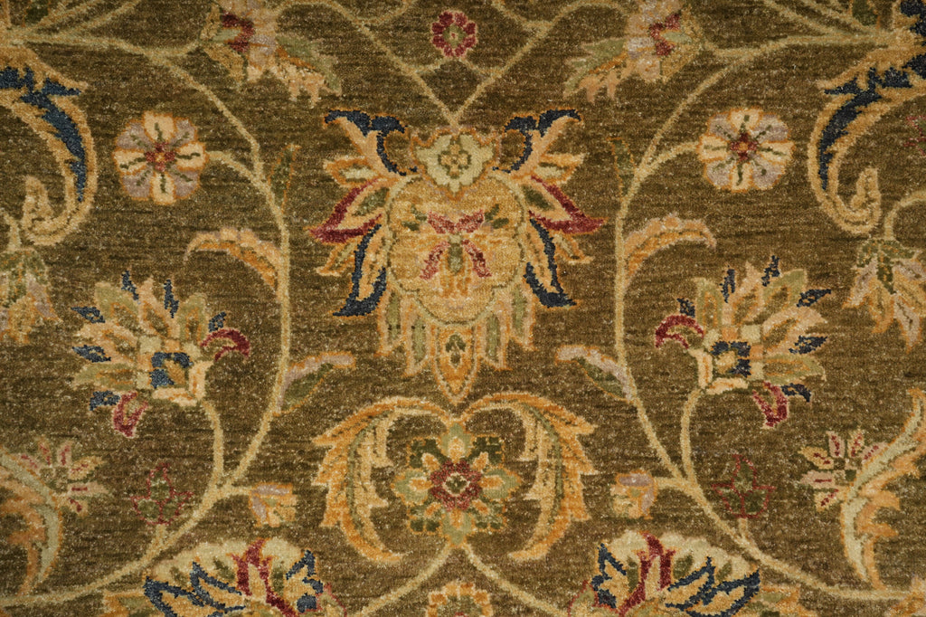 Close-up of an ornate floral rug pattern in olive brown, beige, cream, muted blue, and burgundy, showing detailed woven texture.