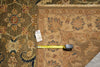 Load image into Gallery viewer, A close-up of a patterned area rug with a beige and brown floral design, shown with a yellow tape measure and a white size tag to indicate scale.