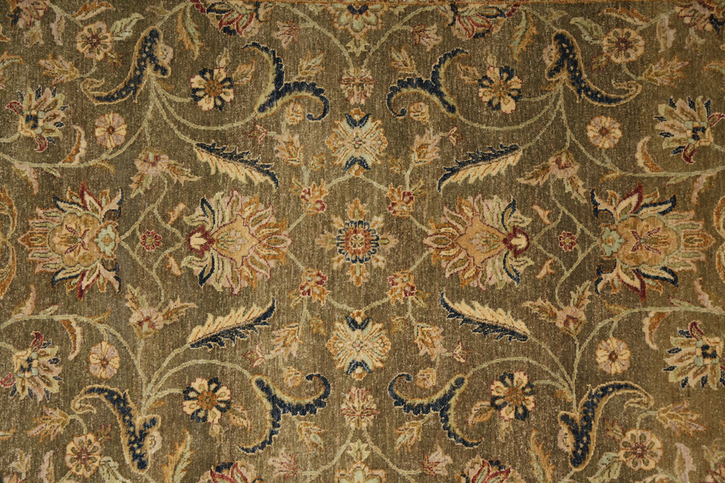 An ornate traditional floral pattern rug in warm olive-brown, beige, and navy blue tones, featuring a symmetrical medallion and scrolling vine design.