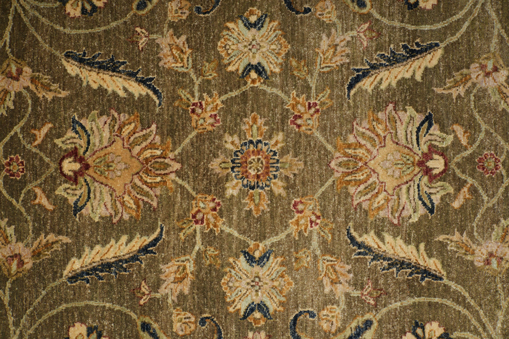A close-up of an ornate floral patterned rug with a warm brown and beige base, featuring cream, mustard, and navy blue details.
