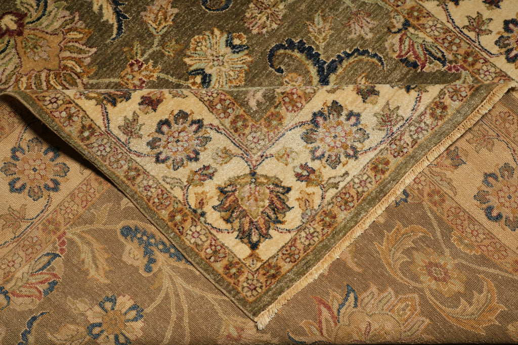 A close-up of an ornate vintage-style area rug showing its corner detail, featuring a beige and olive green floral pattern with blue accents.