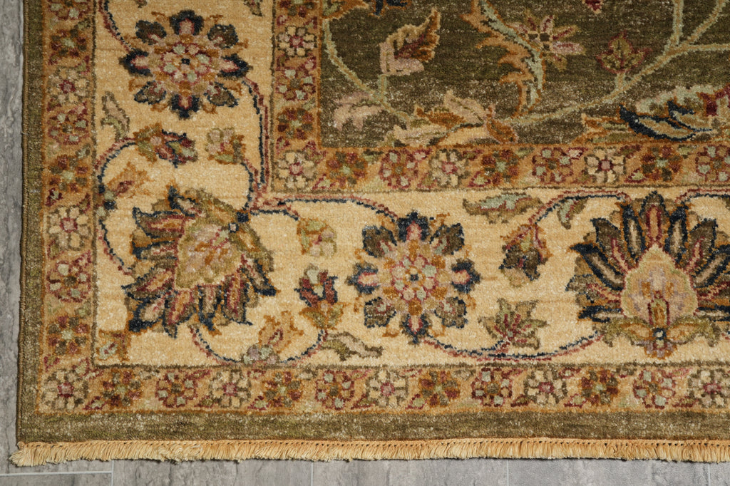 Close-up of a traditional oriental rug corner showing floral motifs and a beige border on a gray floor.