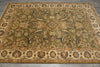 Load image into Gallery viewer, An ornate rectangular area rug with a traditional floral and vine pattern, featuring a warm olive-green center field, beige borders, and accents of navy blue, rust red, and cream, laid out on a gray tiled floor.