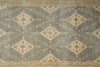 Load image into Gallery viewer, A close-up of a patterned rug with a muted blue-gray field, beige diamond medallions, and tan floral motifs, plus a decorative border along the top and bottom.