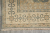 Load image into Gallery viewer, Close-up of a traditional patterned rug corner showing beige, gray, and muted blue-gray motifs with fringe along the bottom edge.