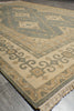 Load image into Gallery viewer, A close-up of a traditional patterned rug with beige, sage green, and brown tones, showing the detailed geometric design and fringed edge.