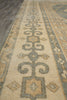 Load image into Gallery viewer, Close-up of a patterned rug with a beige base and gray, blue-gray, and tan geometric motifs.