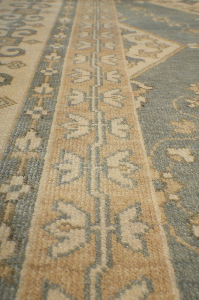 Close-up of a patterned area rug with a beige and slate blue floral design.