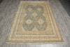 Load image into Gallery viewer, A rectangular area rug with a traditional geometric pattern in beige, gray, and muted green, laid out on a gray wood-look floor.
