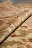 Load image into Gallery viewer, A close-up of a folded area rug with a traditional floral pattern in beige, green, and rust red tones.